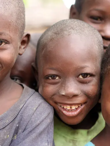 A smiling child stands with some other children