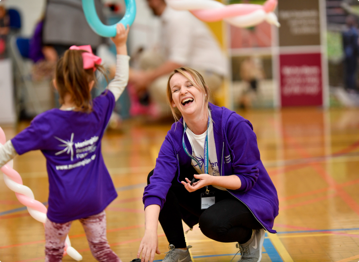 A young child is playing with an woman in a sports hall