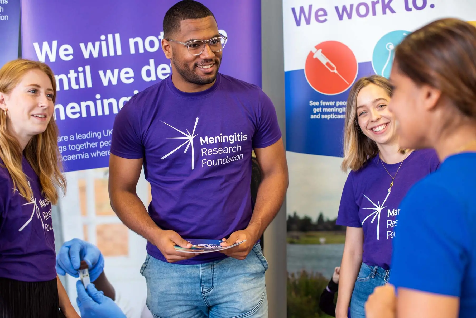 A group of people in Meningitis Research Fondation t-shirts are chatting together